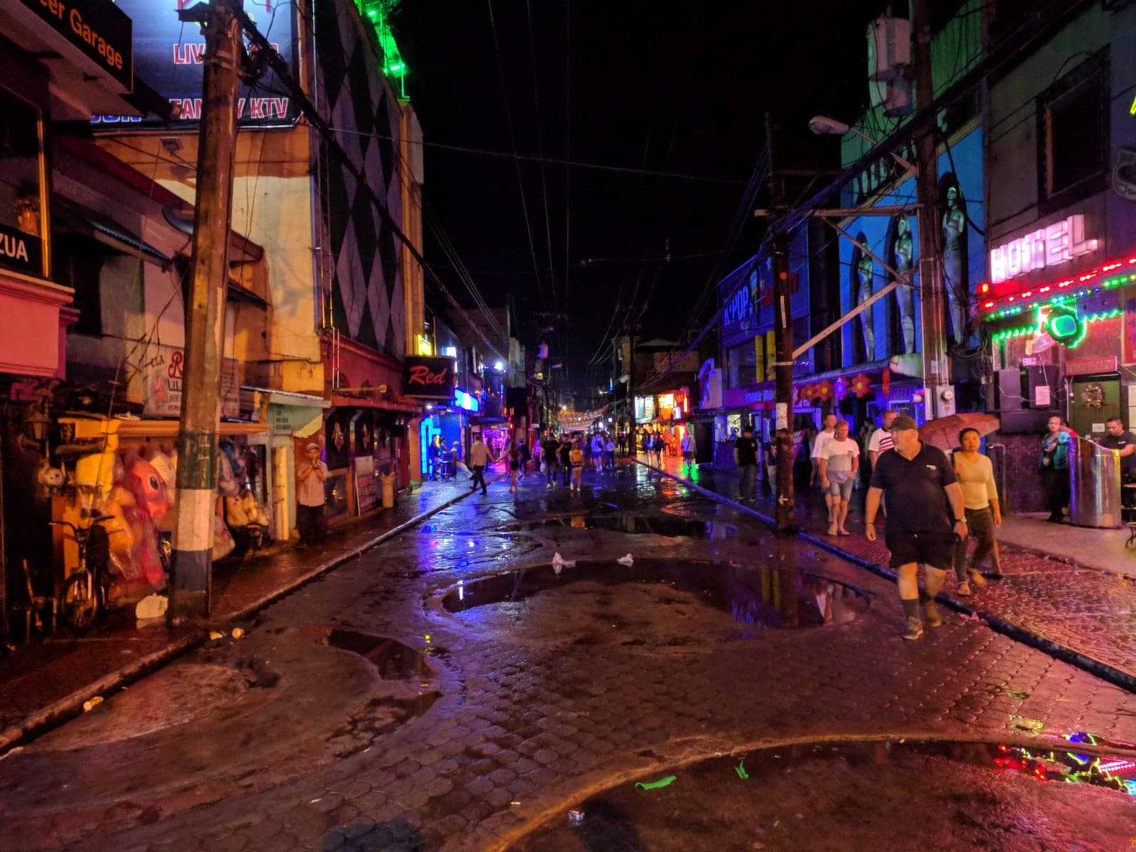 Late-night crowd on Walking Street, Angeles City, with bar neon on both sides of the wet street