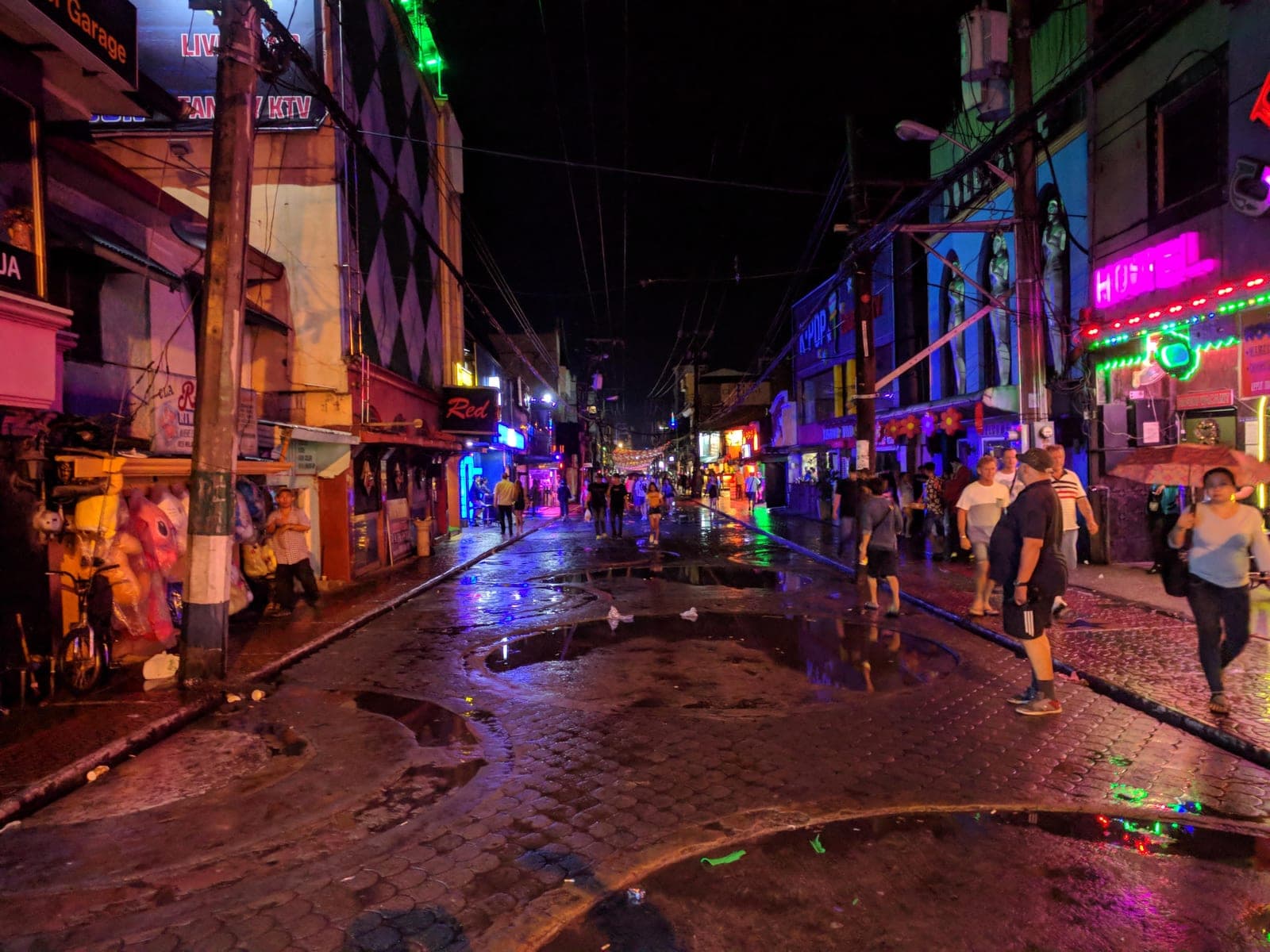 Walking Street, Angeles City, at night after rain — neon signs reflected in the wet pavers